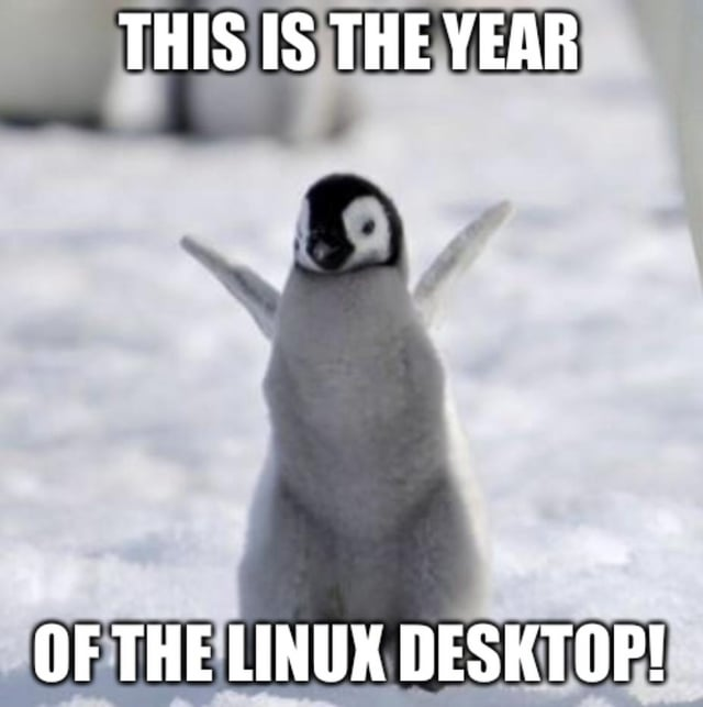 A baby emperor penguin standing on snow with flippers spread wide, captioned 'THIS IS THE YEAR OF THE LINUX DESKTOP!' — referencing Tux, the Linux mascot.